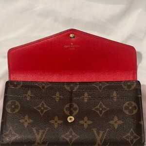 Louis Vitton Monogram Sarah Wallet with red interior.